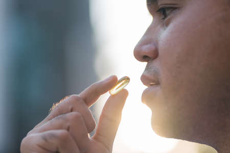 Close up cropped image man holding pill , taking medicine from head ache, stomach pain or taking vitamins, sedation meds, healthcare conceptの写真素材