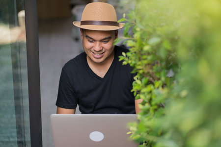 Social distancing concept. Asian handsome man work from home with laptop. Young Casual businessman aged around 30 using laptop for his work.の写真素材