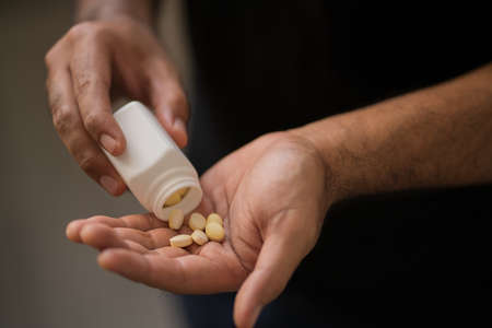 Close up medicine bottle and pills or capsules in hand, palm or fingers. Drug prescription for treatment medication. Pharmaceutical medicament, Antibiotic, vitamins.の写真素材