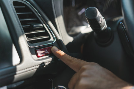 Finger pushing car emergency light button. Man pressing red triangle car hazard warning.