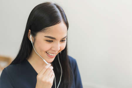 Beautiful asian women conferencing work from home taking on headphones in the morning. Smiling...