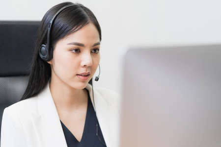 Young business asian woman working call centre customer service agents. Business female support operator with computer and headset in office.の写真素材