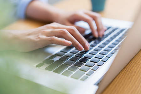 Close up female hand using laptop texting working from home.