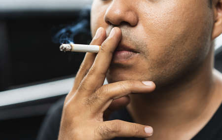 Close up young man smoking a cigarette darknest mood and tone.