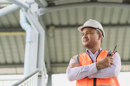 Asian civil engineer operate with radio to control working at construction. Worker wearing hard hat at highway concrete road site. Traffic report concept. Slow motion shot.の写真素材