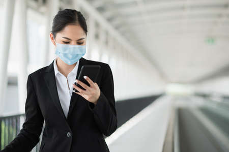 Young asian business woman walking in airport terminal with trolley bag. Beautiful female travel in city downtown.の写真素材