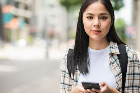 Young Asian beautiful woman travelers use her mobile phones to find travel locations and call for taxi transportation.の写真素材