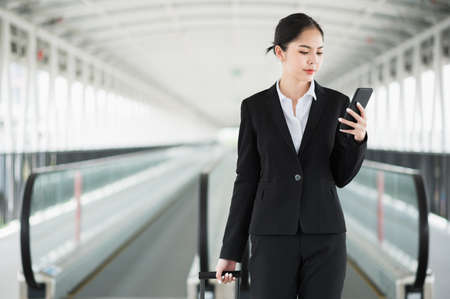 Business woman walking in airport terminal with trolley bag. Traveler female in city downtown.の写真素材
