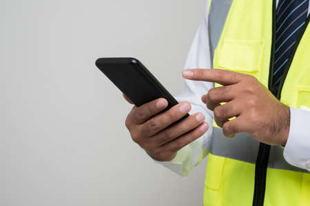 Close up male hands engineer holding mobile phone. Worker using smartphone standing on isolated white background.の写真素材