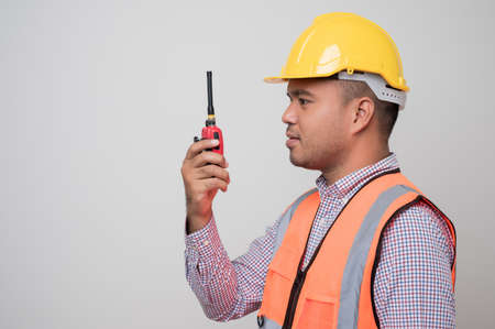 Close up male hand civil engineer holding radio walkie talkie standing in studio isolated white...