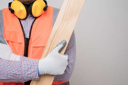 Close up craftsman holding wood standing in studio white background. Carpenter in safety uniform go to working.の写真素材