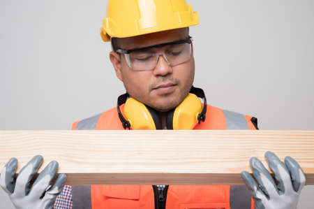 Young asian craftsman checking quality of wood. Carpenter working in studio.