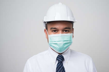 Young asian manager civil engineer helmet hard hat wearing protection mask safety from virus and pollution on isolated white background.の写真素材