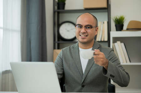 Asian businessman working with laptop computer and drinking coffee.の写真素材