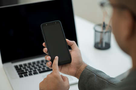 Close up male hands using smartphone and laptop while work from home social distancing concept....