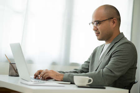 A middle-aged man around the age of 35. Working at home Work through the laptop. He was wearing a...