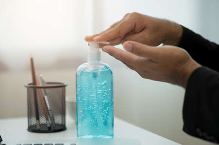 Close-up hand pushing plastic bottle pump with alcohol hand gel.の写真素材
