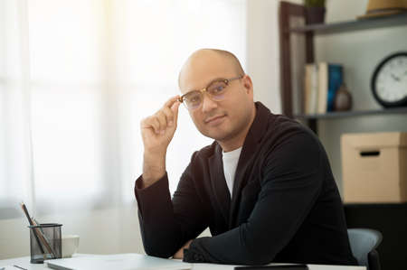 A middle-aged man around the age of 35. Working at home  conference talking on phone and showing thumbs up. He was wearing a grey suit and glasses. Smiling asian businessman work from home.の写真素材