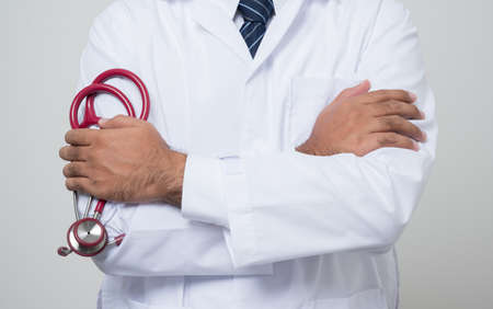 Close Up Doctor in white coat cross his arm with stethoscope in his hand
standing middle isolated on white background.の写真素材