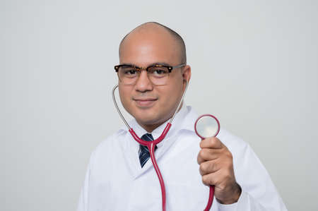Doctor in white coat, stethoscope cross his arm and thumb up look into
camera with smile beside corner isolated on white background.の写真素材
