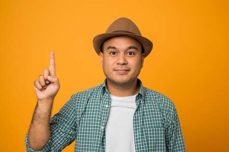 Tourist man on vacation showing and pointing up with fingers number one while smiling confident and...