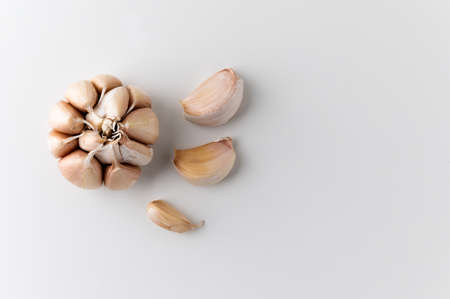 A lot of Garlic cloves and pieces of raw garlic on isolated white background. Top view Garlic bulbs...