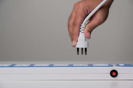 Close up Hand holding Electric plug put on multiple socket. Electrical equipment, electrical wires...