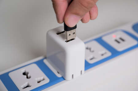 Male hand put the usb cable into plug with multiple socket for charging the battery. Electrical...