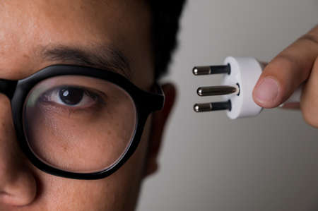 Man holding plug cable near his head. Show the symbol of electricity consumption. Electrical...