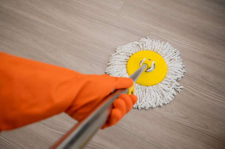Cleaning workers mopping the wet area. There was spill water on the wooden floor in the living room....