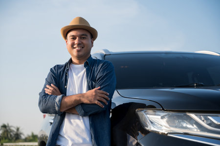 Young handsome asian man getting the new car.He standing in front of the car.He very happy. Buy or rent a car concept.の写真素材