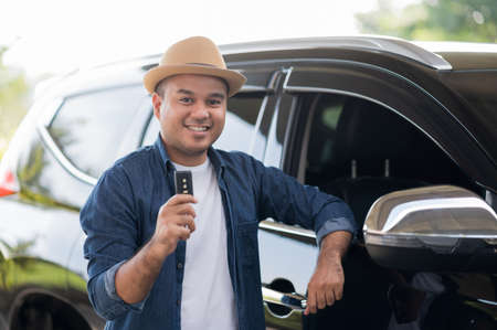 Young handsome asian man getting the new car.He showing car key and very happy. Buy or rent a car...