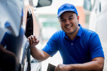 A car maintenance worker is checking the quality of the tires that are worn out, should they be replaced or not He takes care of the car for the customer.の写真素材