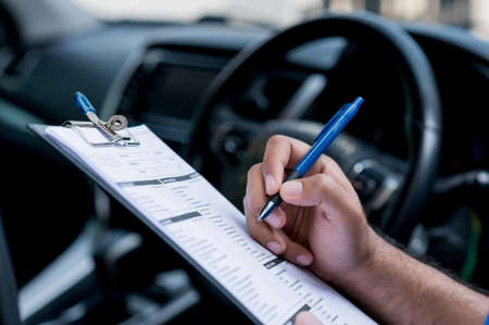 A car maintenance worker is checking a list of the car interior for a workshop customer.の写真素材