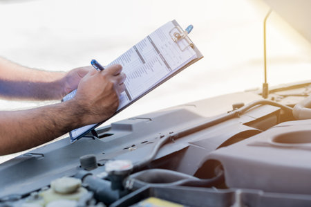 A car maintenance worker is checking a list of the car engine for a workshop customer.の写真素材