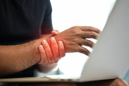 Man work so hard and long time that he has office syndrome. He has wrist pain, from working with laptop.の写真素材