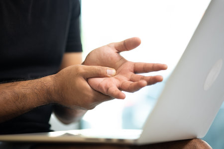 Man work so hard and long time that he has office syndrome. He has wrist pain, from working with laptop.の写真素材