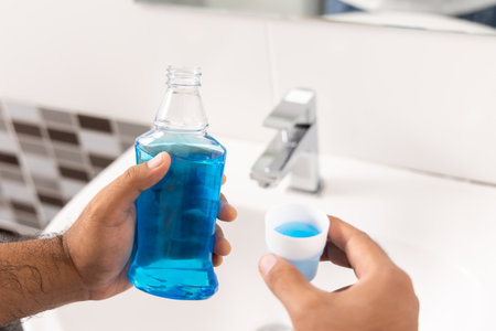 Young man is gargling with a blue mouthwash. For good dental health and fresh bad breathの写真素材