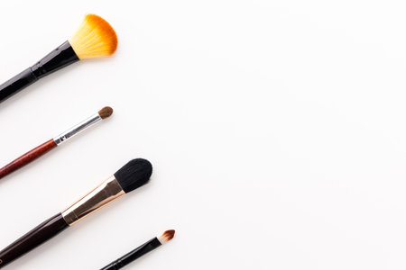 Eye shadow brush and powder brush of various sizes arranged beautifully on a white table. With copy...