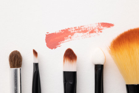 Top view cosmetics makeup for female on the white table background with Different brush types.
