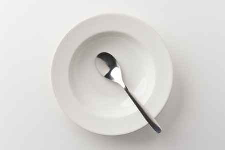 A white plate on a white table with a spoon There is no food on the plate. Household equipmentの写真素材