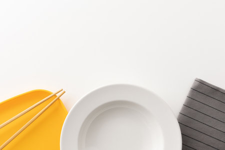 Kitchen sets, plates, napkins and chopsticks are placed together on a white table.の写真素材