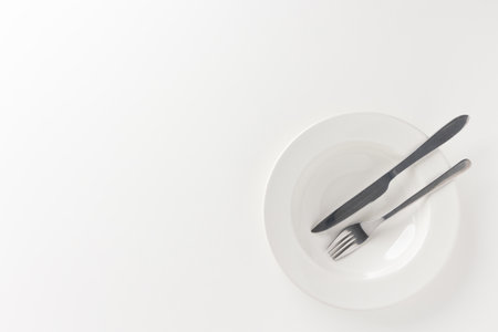 The empty white plates were set on the table with knives and forks. Ready to eatの写真素材