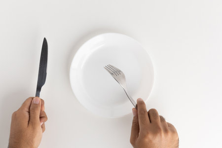 A man with a knife and fork to eat on the plateの写真素材