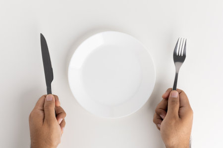A man with a knife and fork to eat on the plateの写真素材