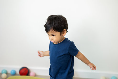 An Asian boy about 1 year old. Take a walk in the living room of the house. He is wearing a blue...
