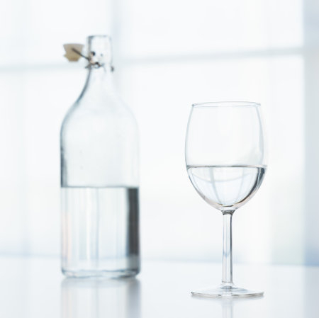 A glass of water and a clear glass water bottle are placed on the table in the house on a white background.の写真素材