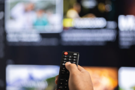 Close up male hand holding remote control pointing to change the programme television.の写真素材