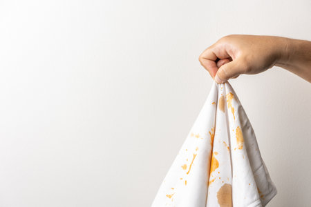 White cotton shirt A lot of stains, stains, coffee stains, man's hand holds the shirt up and spreads it to look dirty Must be brought to the washing machineの写真素材