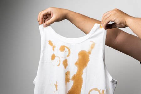 White cotton shirt A lot of stains, stains, coffee stains, man's hand holds the shirt up and spreads...